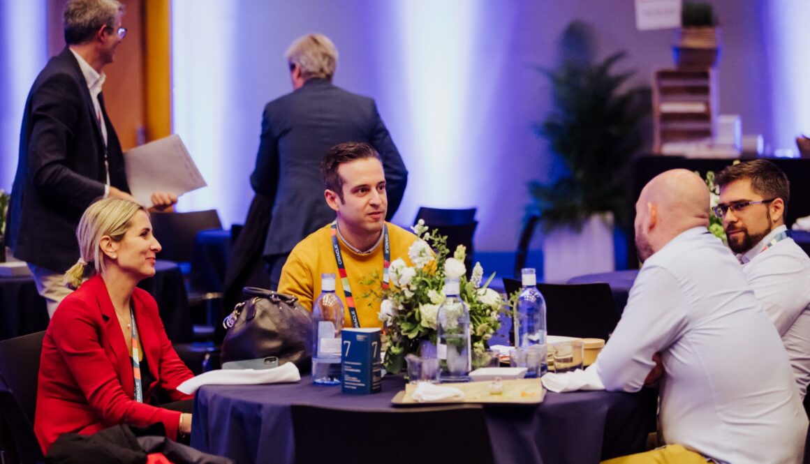Corporate summit in Spain with attendees networking and engaging during a keynote presentation, showcasing a well-organized professional event setup.