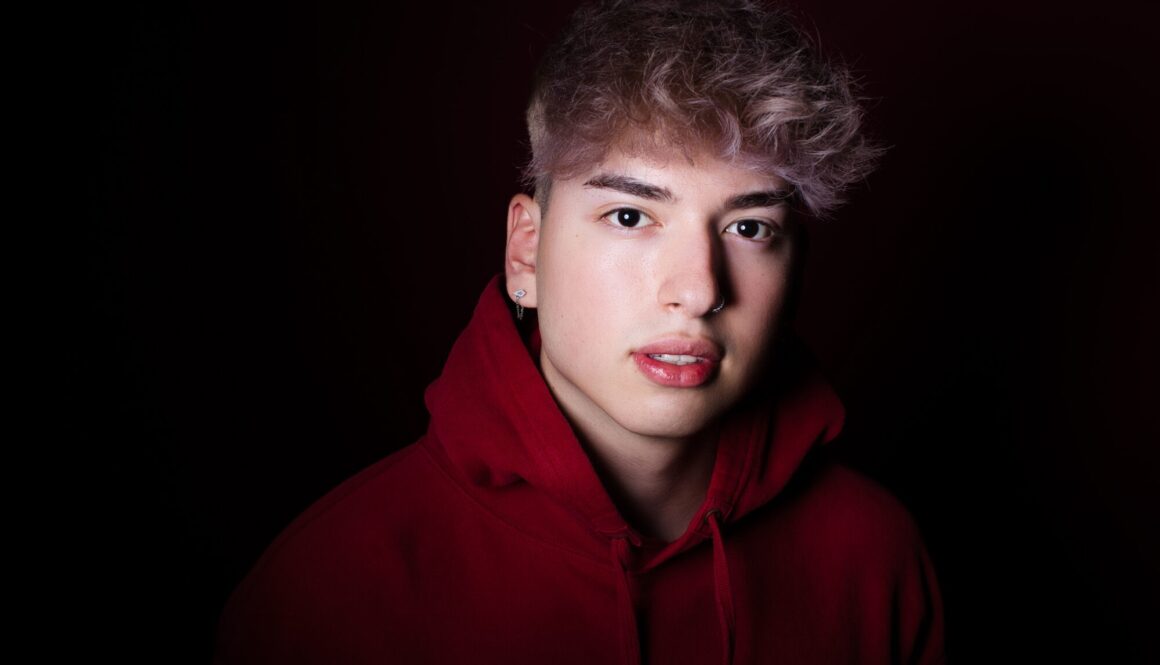 Retrato en estudio de joven con sudadera roja, ideal para fotografía de perfil impactante.