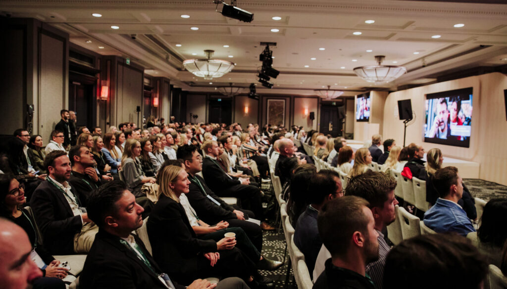 Event photography budget: full audience following a conference session in a hotel ballroom