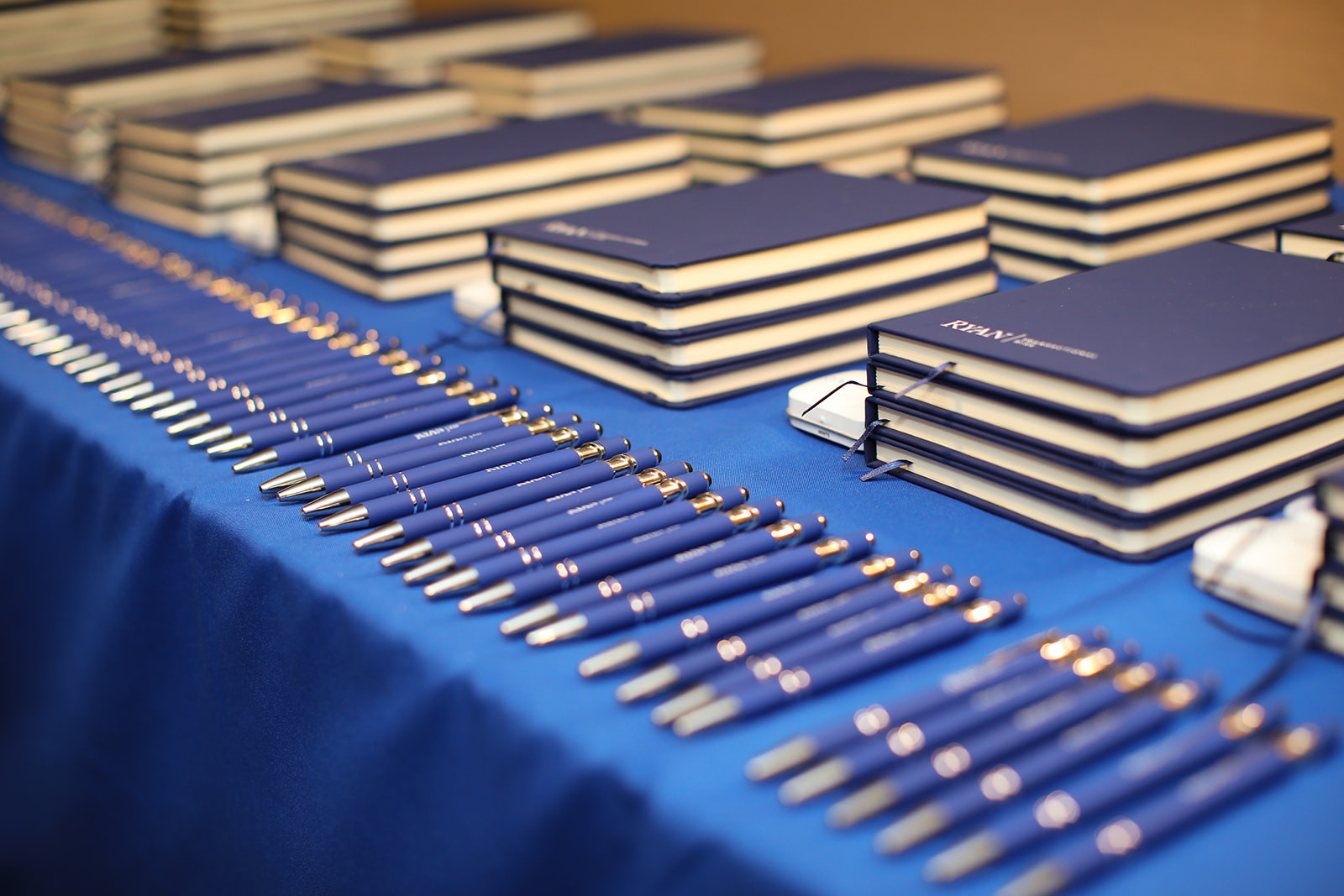 Rows of branded notebooks and pens prepared for attendees at a corporate event